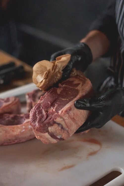 butcher wiping raw steak with a paper towel