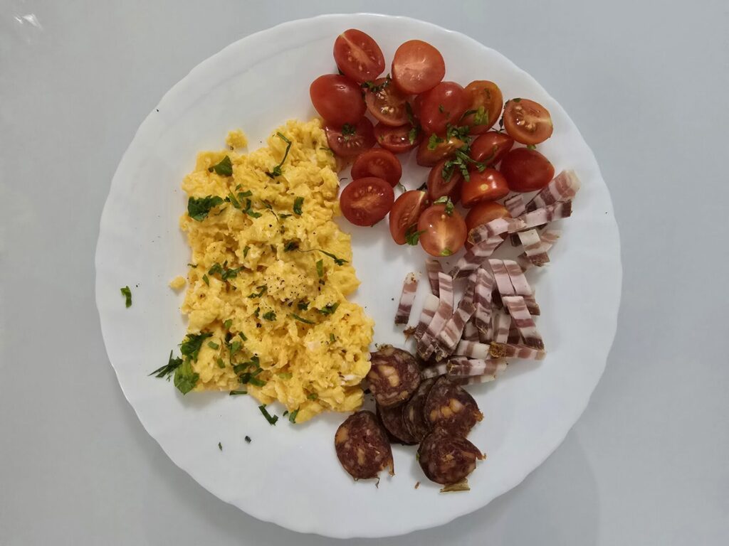 scrambled eggs with bacon, sausages and cherry tomatoes
